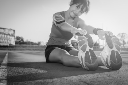 Young woman stretching on a running track ,  black and white.の写真素材
