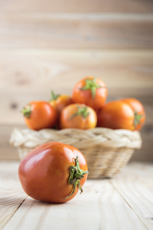 tomatoes in basket on wooden tableの写真素材