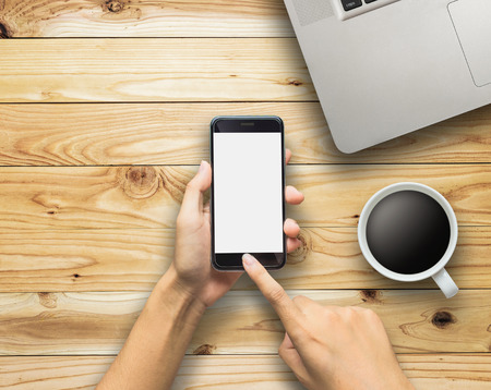 hand using phone laptop and coffee cup on woodの写真素材
