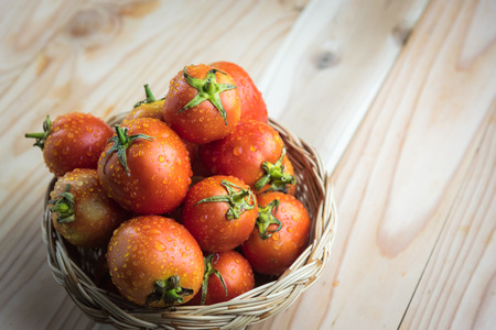 tomatoes in basket on wooden tableの写真素材