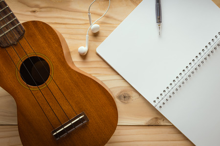 Ukulele guitar with earphone on wooden tableの写真素材
