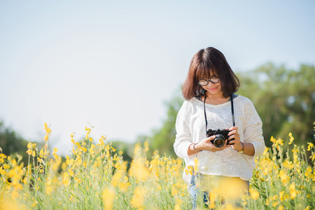 Young woman with camera in the Sunhemp gardenの写真素材