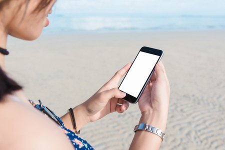 Beautiful woman's hand using smart phone at beach.の写真素材