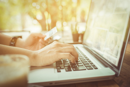 Hands holding plastic credit card and using laptop, vintage toneの写真素材