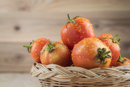 tomatoes in basket on wooden tableの写真素材