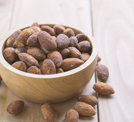 Almonds in the wooden bowl on the table, close-upの写真素材