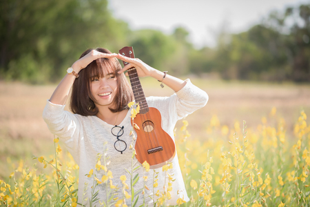 Young woman playing on Ukulele on Sunhemp backgroundの写真素材