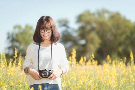 Young woman with camera in the Sunhemp gardenの写真素材