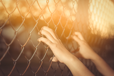 Hand holding on chain link fenceの写真素材