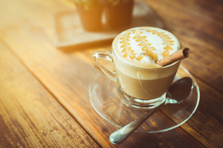 A cup of cafe latte on wood , orange sunshine ,  vintage toneの写真素材