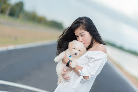 Asian woman beautiful young happy with long dark hair  holding small dog.の写真素材