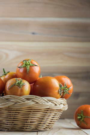 tomatoes in basket on wooden tableの写真素材