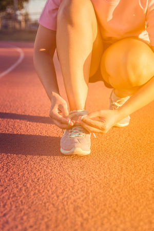 Female athlete tying laces for jogging , sunsetの写真素材