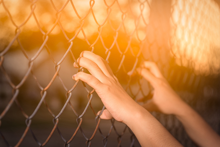 Hand holding on chain link fenceの写真素材