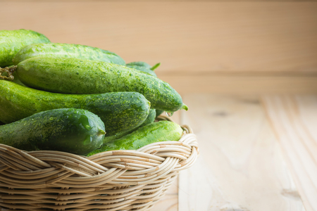 Fresh cucumbers in basket on woodの写真素材