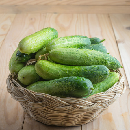 Fresh cucumbers in basket on woodの写真素材