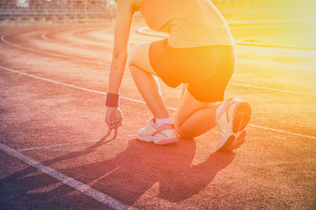 Athletic woman in start position on track  , sunset , vintage toneの写真素材