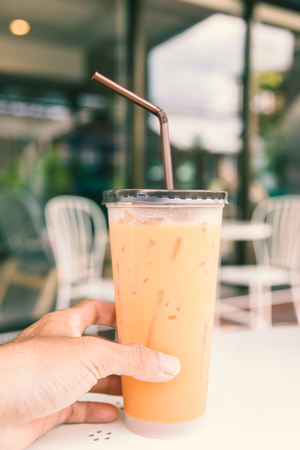 Iced Milk Tea with straw in plastic cup on a  table in summer , vintageの写真素材