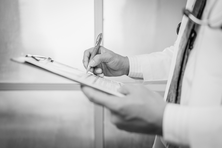 Close-up Of Male Doctor Filling The Medical Form , black and white.の写真素材
