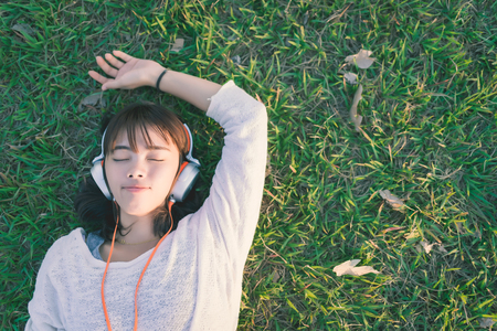 Relaxed woman listening to the music with headphones lying on the grassの写真素材