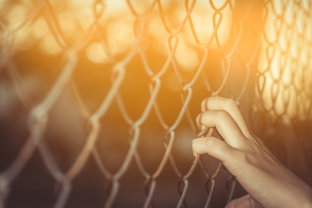 Hand holding on chain link fence,  vintage toneの写真素材
