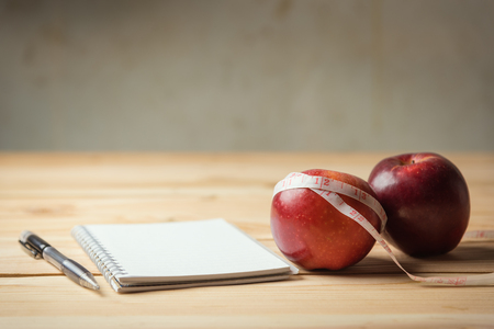 apple, tape measure and notepad  lying on a woodeの写真素材