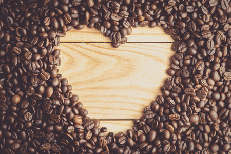 Heart shape made from coffee beans on wooden surface , vintage toneの写真素材