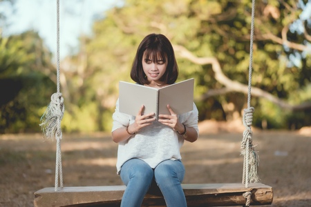 smiley young woman holding a book outdoorsの写真素材