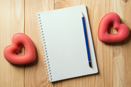 A notebook is lying on a light wooden table. The note book is open on 14th February, Valentine's Dayの写真素材