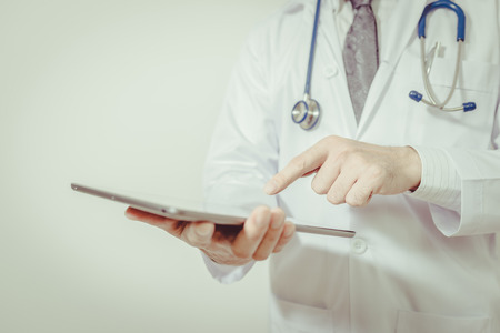 Doctor using a digital tablet on white background , vintage toneの写真素材