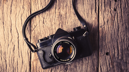 Retro camera on wood table background, vintage color tone.
