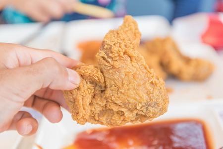 Hand holding Fried chicken and eating in the restaurantの写真素材