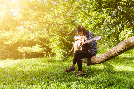 Female fingers playing guitar outdoor in summer park. Musician woman and her guitar in nature park, Practice guitar.の写真素材