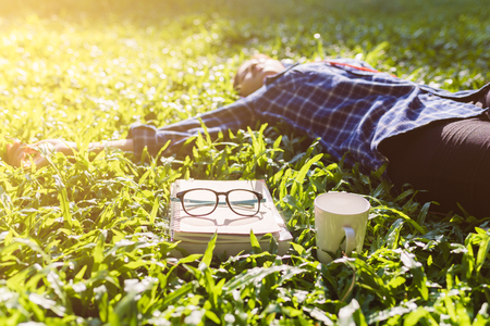 Books and glasses on grass in the park. Women listen to musicの写真素材
