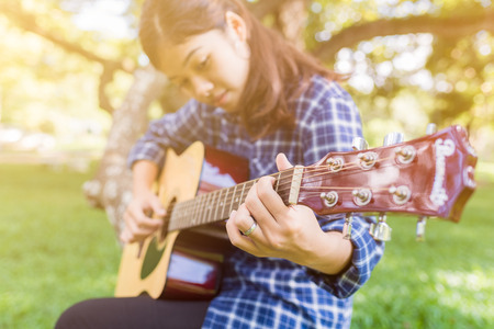 Female fingers playing guitar outdoor in summer park. Musician woman and her guitar in nature park, Practice guitar.の写真素材