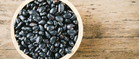 Black beans in wooden bowl. Top view. Copy space. wood background. vintage tone banner panoramic crop for copy space.の写真素材