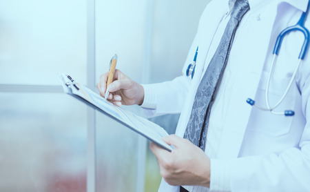Close up Of Hand Male Doctor Filling The Medical Form. の写真素材