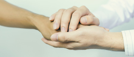 Two people holding hands for comfort. Doctor consoling relatives of patients in hospital concept banner panoramic crop for copy space.の写真素材