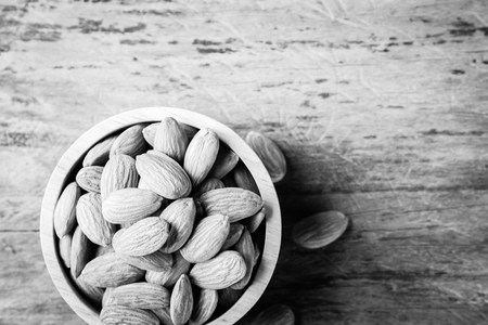 Almonds in brown bowl on textured wooden background, top view.の写真素材