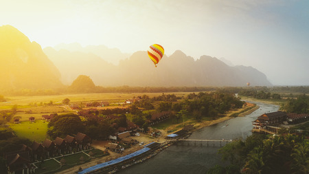 Aerial view by Drone : Hot air balloon over Nam Song river in Vang vieng, Laos on sunset, vintage...