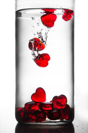 red hearts falling in glass of waterの写真素材