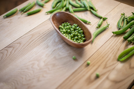 pea pods on the table and plate full of peasの写真素材