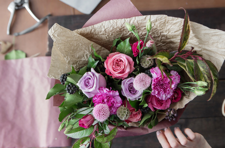 florist's hands covering flowers on wood backgroundの写真素材