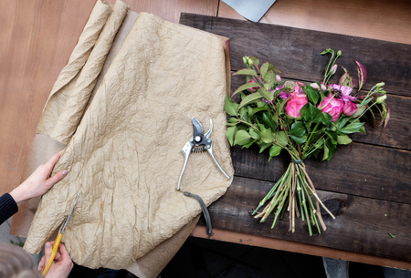 florist's hands cutting paper for covering flowersの写真素材