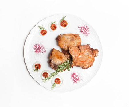 dish of pork with sauce and garnish isolated on whiteの写真素材