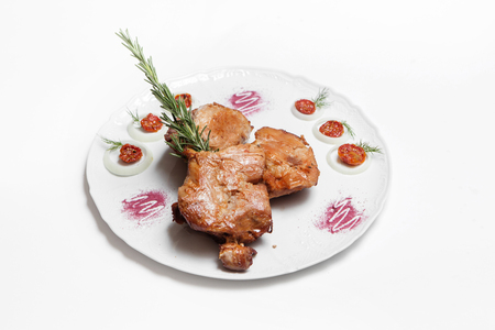 dish of pork with sauce and garnish isolated on whiteの写真素材