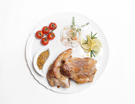 dish of pork with sauce and garnish isolated on whiteの写真素材