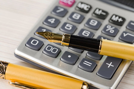 Calculator and pen on wooden table, closeup. Accountingの写真素材