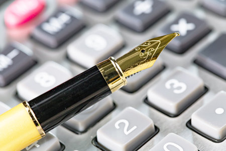 Closeup of a fountain pen on a calculator, shallow depth of fieldの写真素材