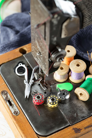 Sewing tools on the table. Sewing machine, spools of thread, needles and buttons for sewing.